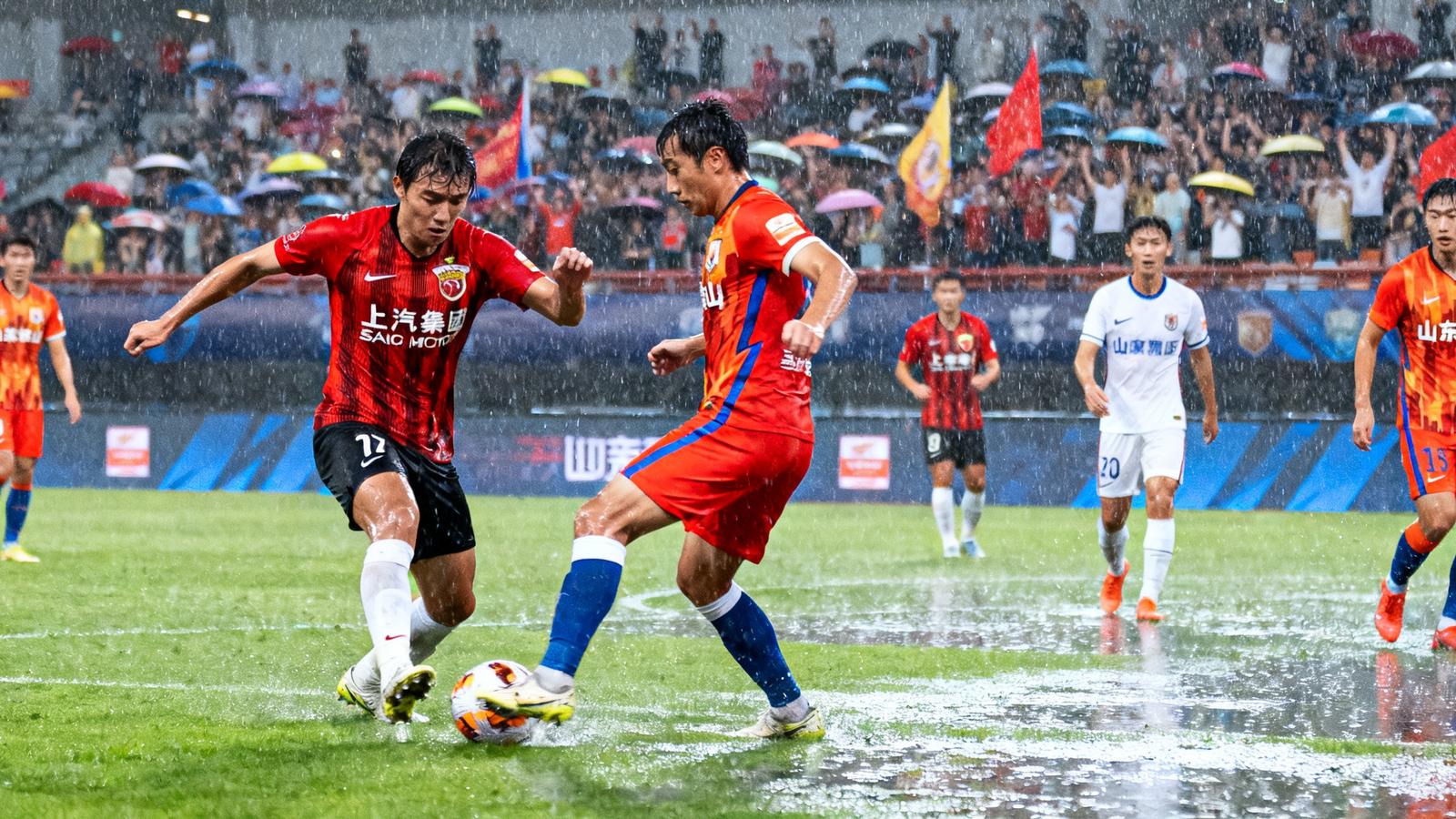 中超联赛上海海港与山东泰山的激烈对决，球员在雨中奋力拼抢，观众席热情高涨